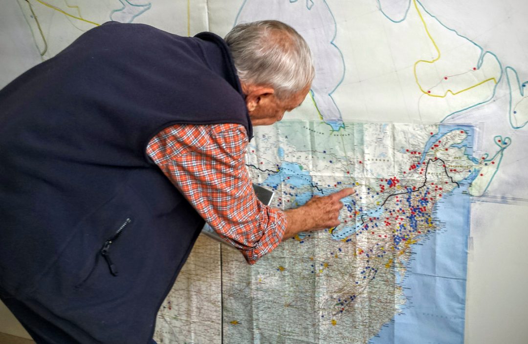 John Andrew points out ski areas he's skiied on a the wall-sized map in his Renton, Wash., home. Credit: John Nelson